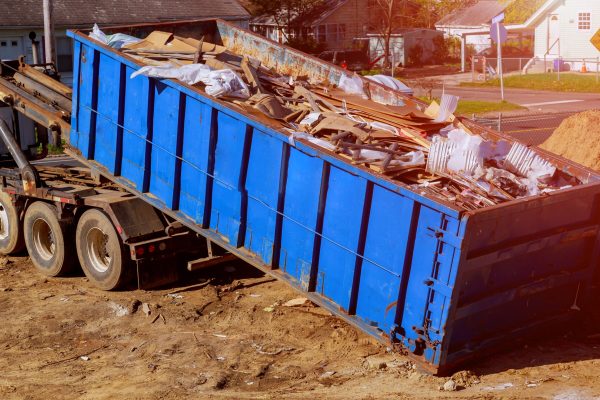 Industrial garbage bin blue construction debris container filled with rock and concrete rubble.